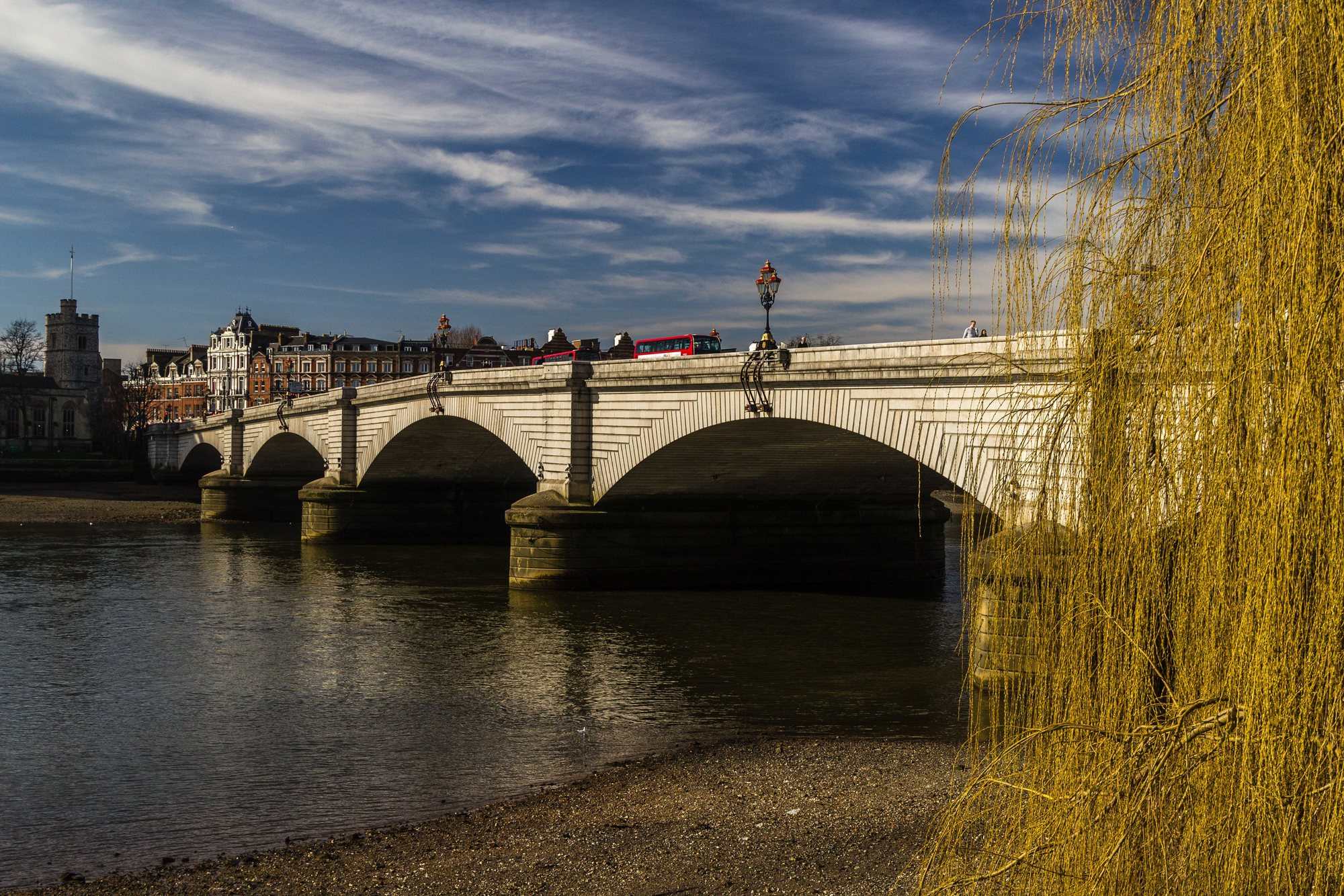 Putney Bridge and its stone arches over the Thames at low tide, seen from the Putney foreshore